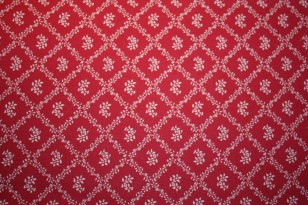 Tissu : petites fleurs et losanges taupe sur fond rouge foncé